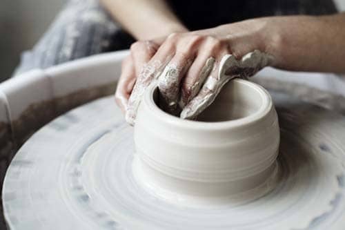 person making clay bowl on pottery wheel