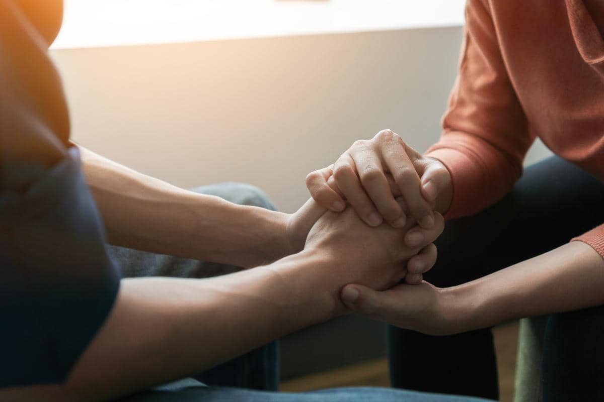 two people holding hands while talking about the levels of addiction treatment care