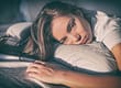 depressed woman in bed hugging pillow displaying one of 5 signs of alcoholism in women