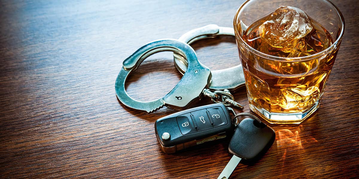 Car keys and glass of alcohol on table leads to the question of the difference between dui vs dwi