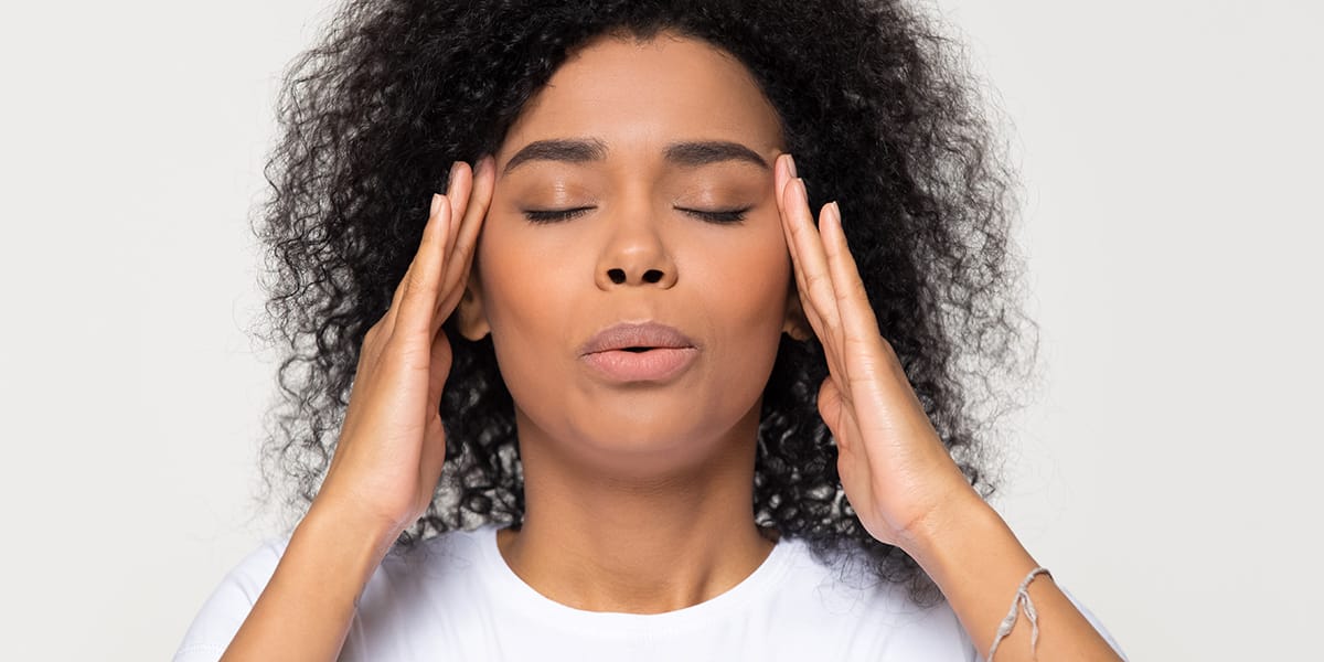 woman with her hands on her head breathing deeply displaying staying in the moment when you have anxiety
