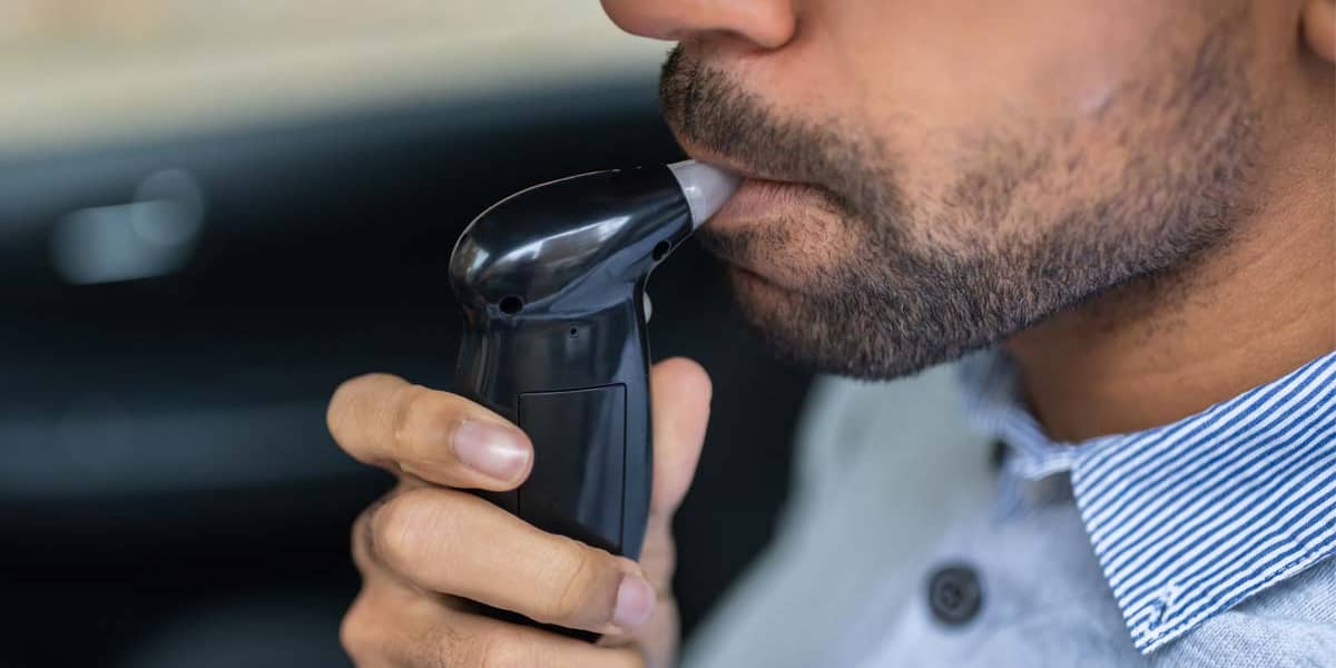 a man uses a breathalyzer after drunk driving