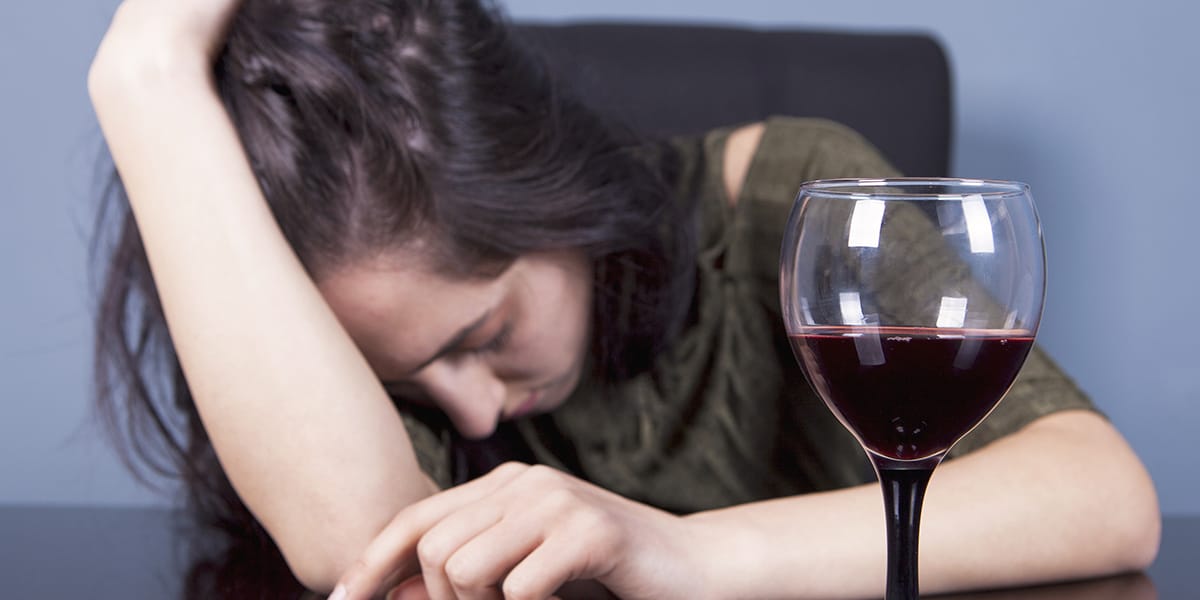 a woman feeling ill after experiencing the dangers of binge drinking