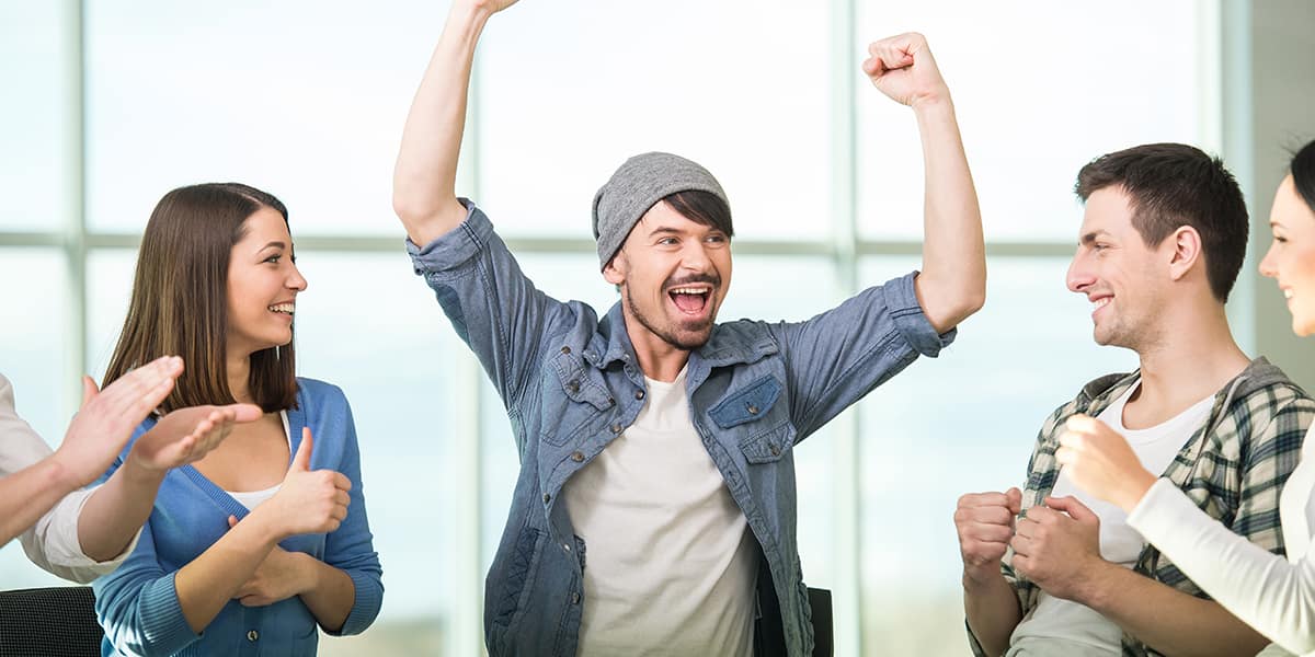 A man cheering in group therapy because he has a support system for recovery