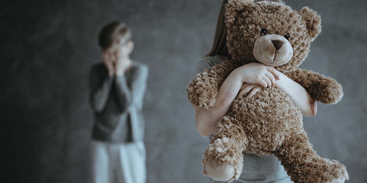 a young child holding a teddy bear while not understanding childhood trauma and addiction