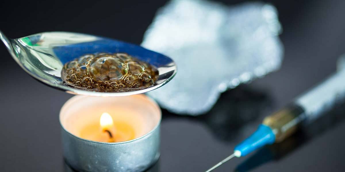 spoon of heroin over a candle next to a syringe displaying the need for heroin treatment facilities in FL