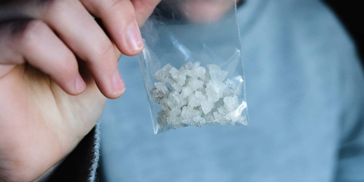 individual holding up a baggy of meth to show the effects of meth