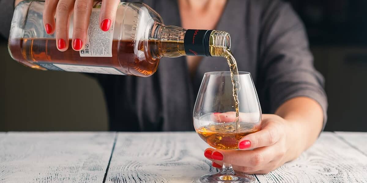 a person pours a drink ignoring Alcohol Awareness Month