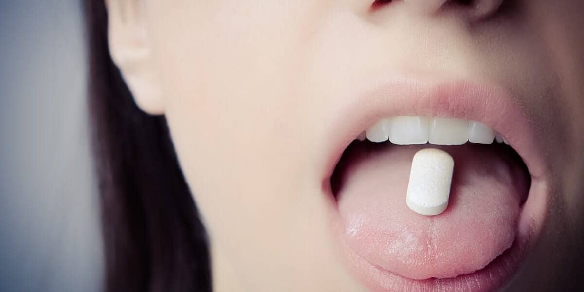 a woman holds a pill on her tongue thinking about the long term effects of xanax