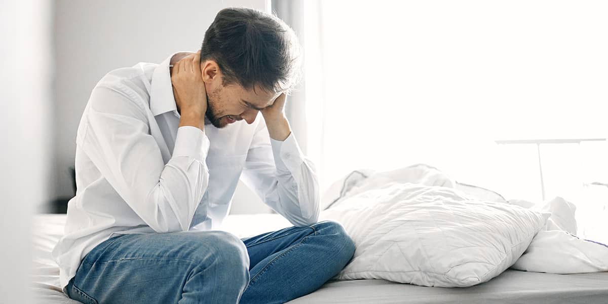 man on bed with head in hands concerned about compromised immune system