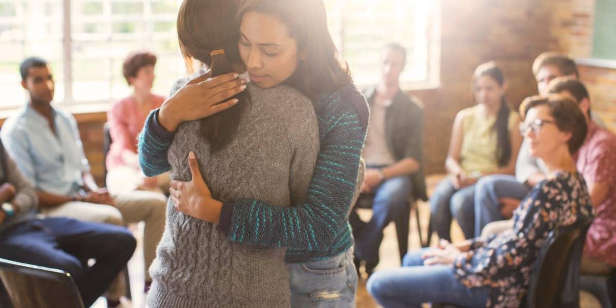 two women hugging to stop being lonely in addiction recovery