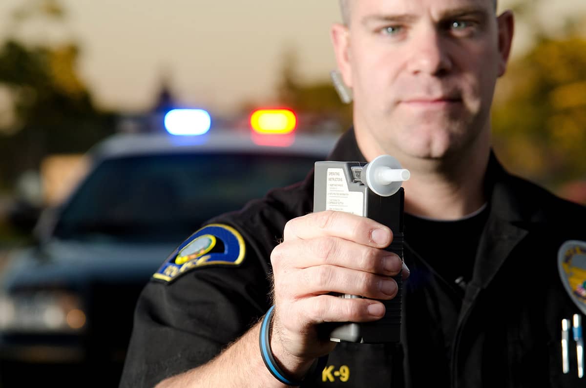 a police officer holding a breathalyzer to test for dui vs dwi