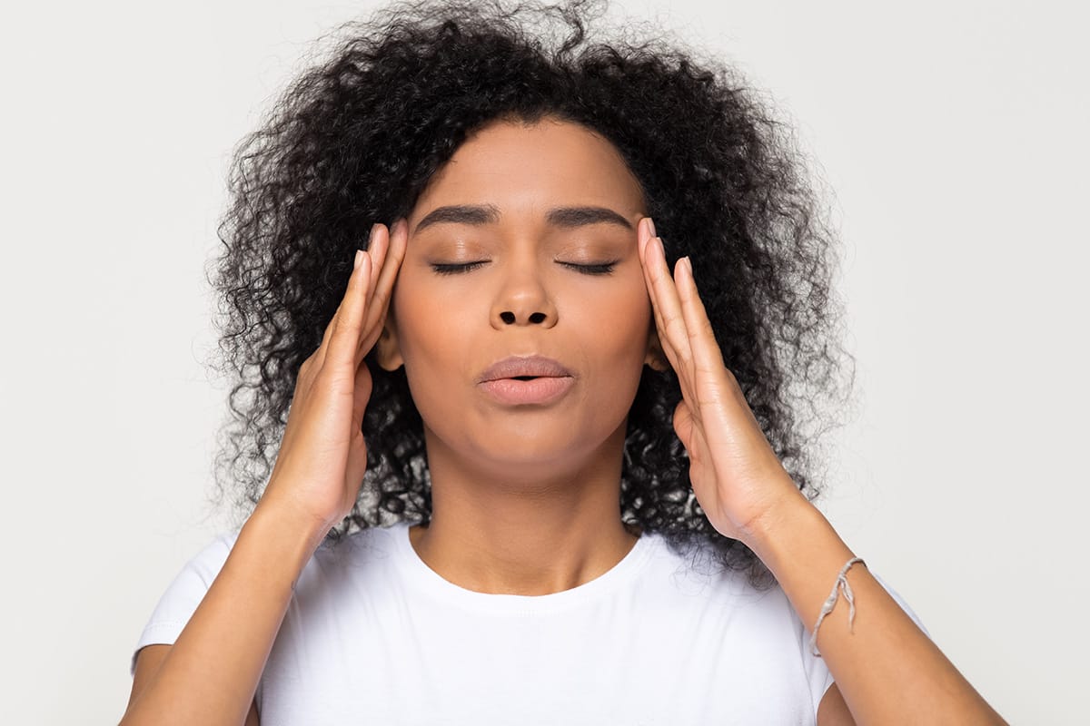woman with her hands on her head breathing deeply displaying staying in the moment when you have anxiety