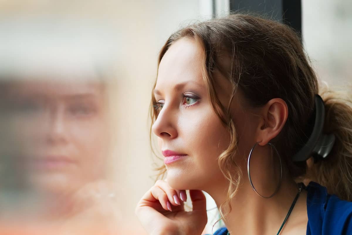 a woman looking out the window thinking about stress management