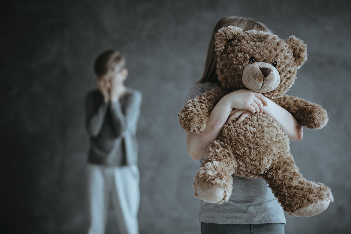 a young child holding a teddy bear while not understanding childhood trauma and addiction