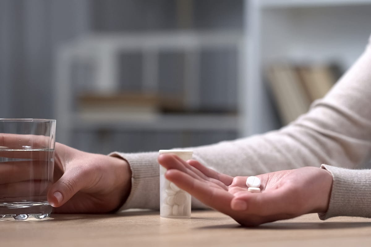 a person taking pills who needs a painkiller rehab