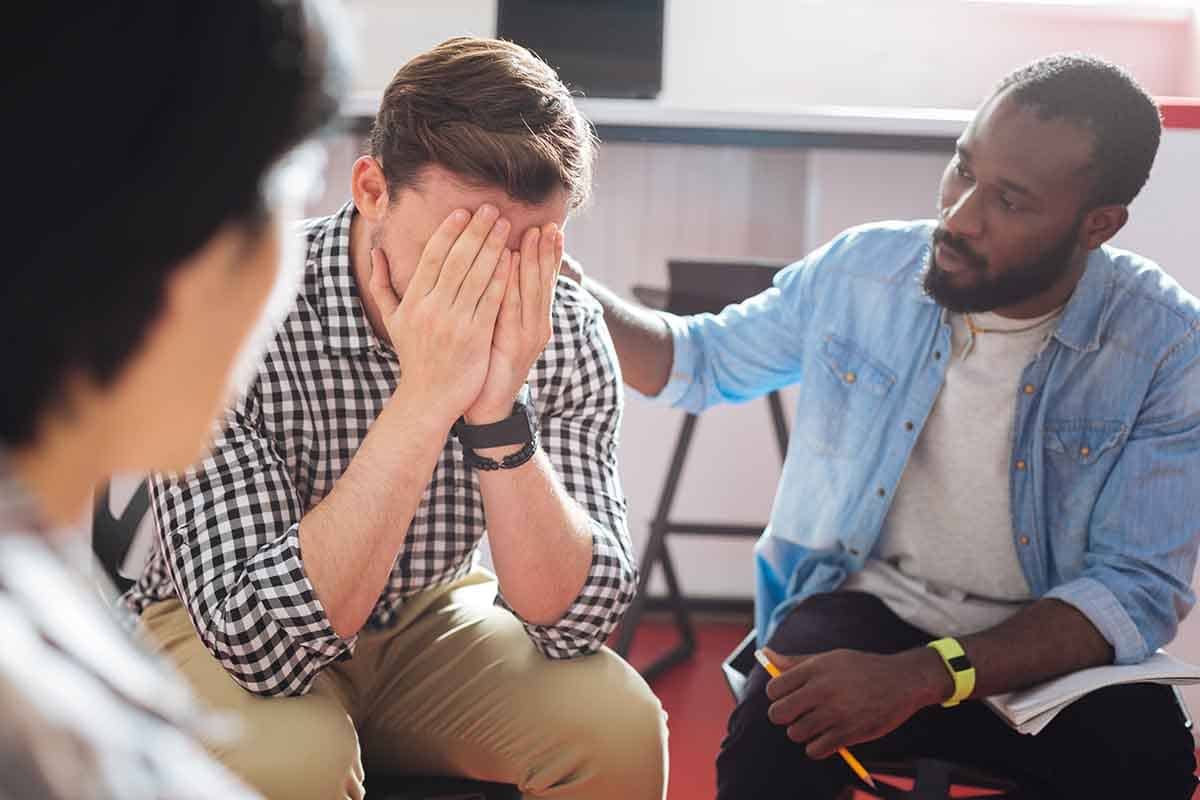 two men comforting each other in rehab