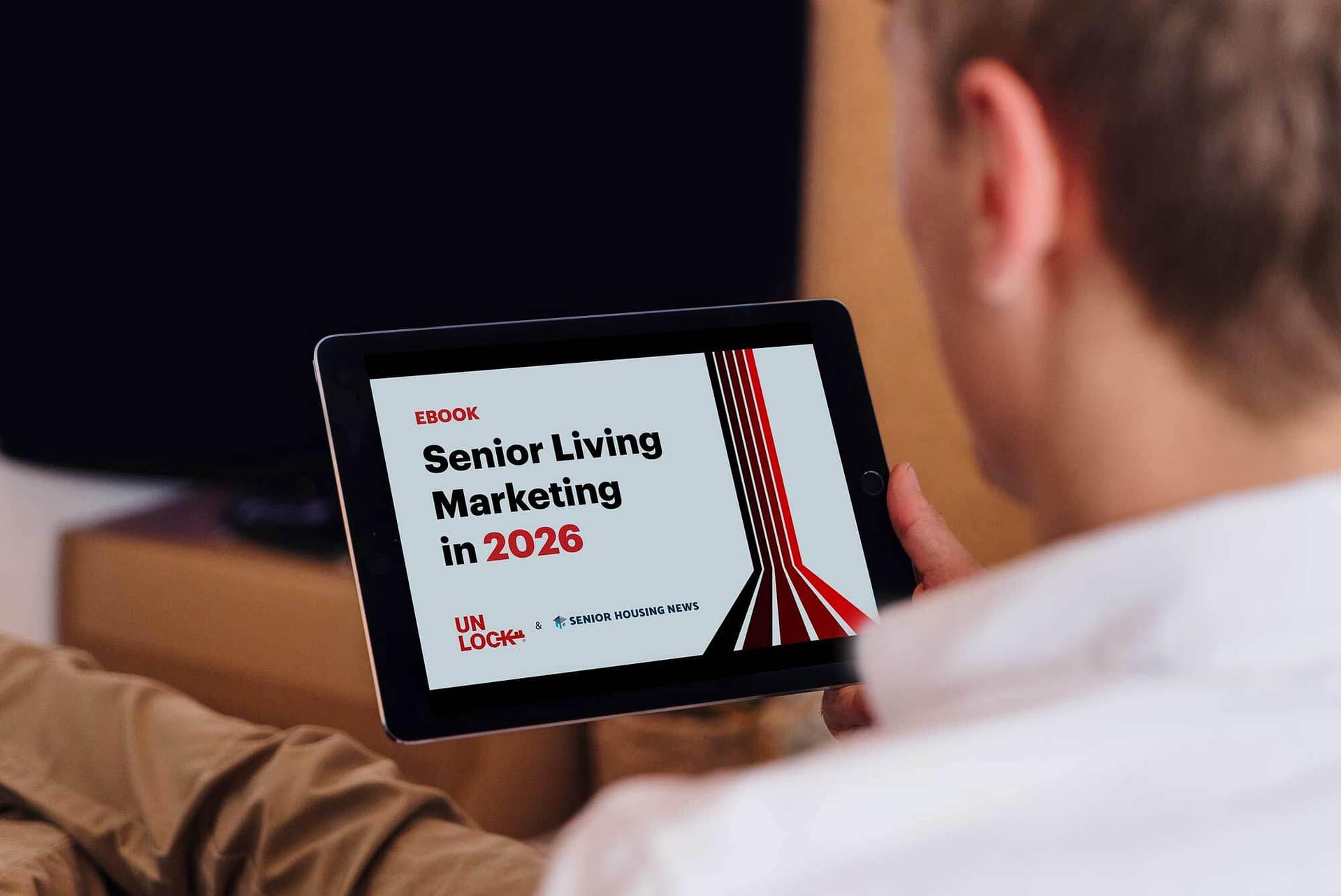 A person holds a tablet while reading the "2026 Senior Living Marketing Survey Report."