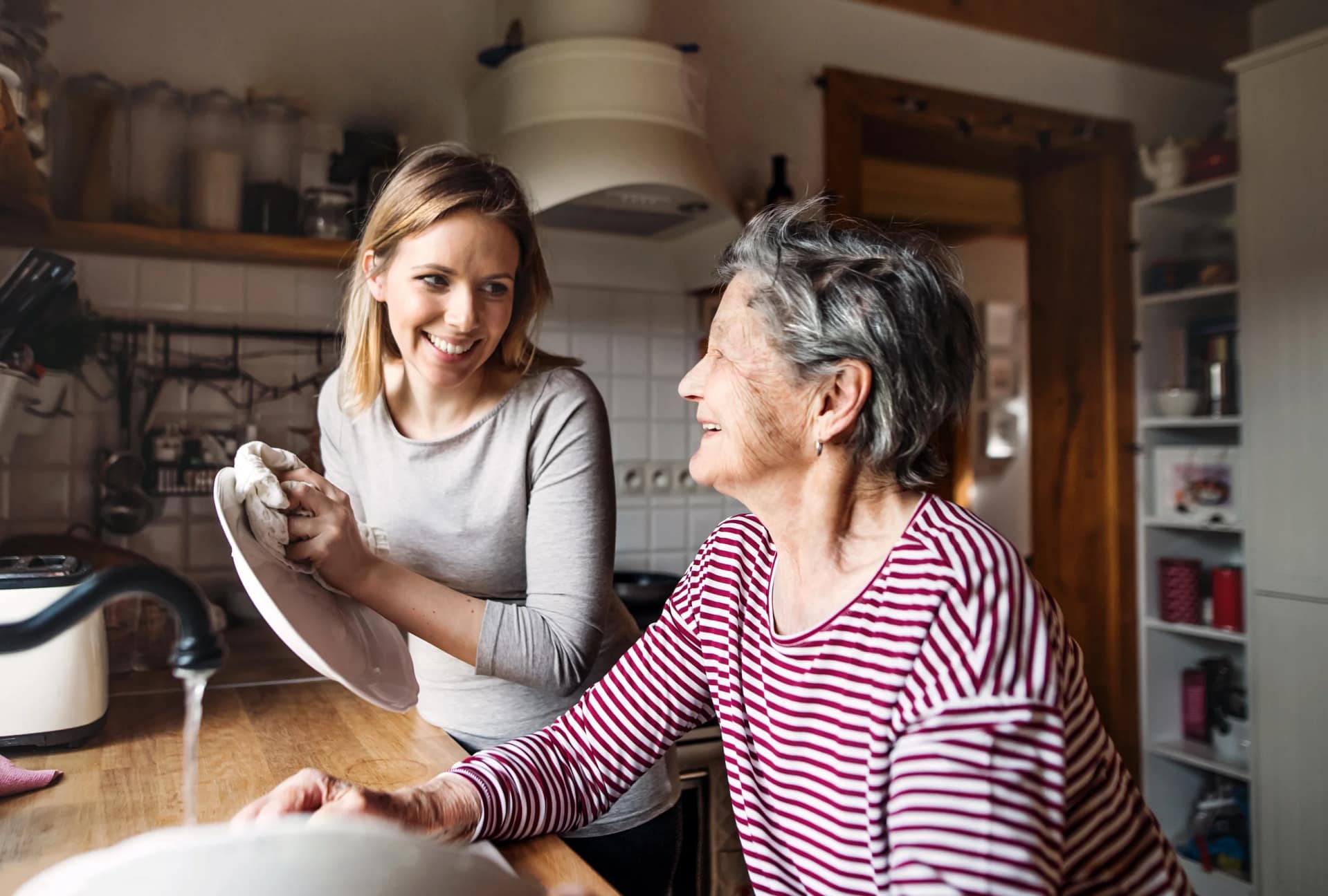 Woman washing dishes with elderly woman.