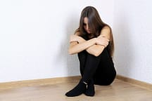 Addicted woman hugging herself in corner needs a detox for women.