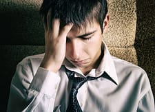 Young man in tie with hand to head needs Beaches Recovery in Florida for his addiction treatment