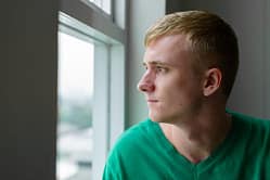 Teen drug abuse has this young man looking out window in detox.