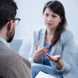 Woman out of focus talking to therapist about therapy vs counseling