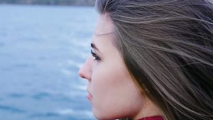 Sad young woman looking out over the water feeling meth withdrawal.