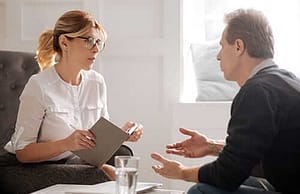 Man talking to female counselor asking about alcoholic treatment program