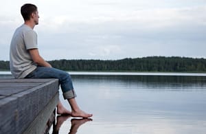 Man sitting on dock wondering when will I be sober