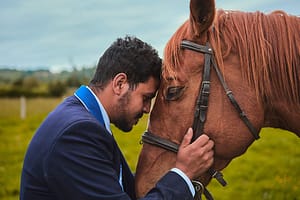 a young man in an equine therapy program puts his face to a horse's