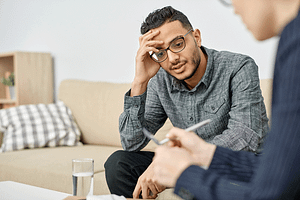 a young man talks with a therapist in an ocd and anxiety treatment center