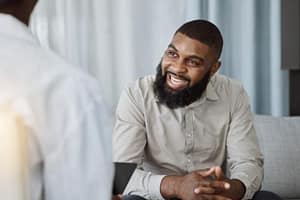 a young man smiles at a therapist during a 12-step recovery program
