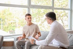 a young man and therapist discuss inpatient mental health facilities