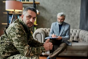 a man in uniform talks to a therapist at a PTSD treatment center