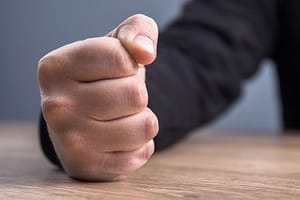 someone in need of anger management classes with their fist on a desk