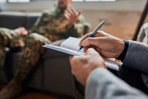 a therapist takes notes in front of a servicemember during therapy for veterans