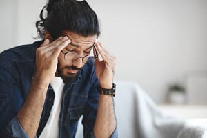 a man sits and rubs his head after stopping alcohol cold turkey