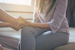 Woman sitting and holding hands in women's residential treatment program