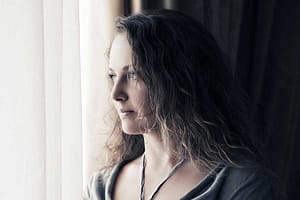 woman looking out window wonders why do people do drugs
