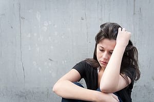Distressed woman against wall with hangover wants to fix her physical addiction
