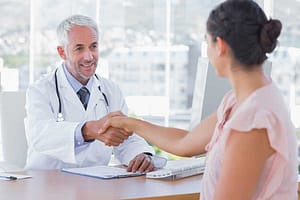 Doctor shaking hand of woman across desk asking about the detoxification process