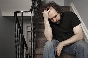 Man sitting on stairs with hand to head going through vicodin withdrawal