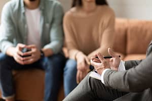 Couple sits on couch and talks to therapy after starting couples therapy to improve communication