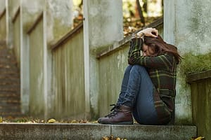 Girl going through morphine withdrawal on her own, sitting a concrete steps.