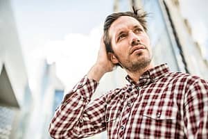 Man in plaid shirt glad to be at a halfway house after a bad day at work.