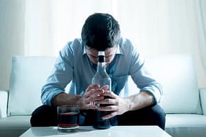 Xanax and alcohol have put this man sitting on a couch into a depression.