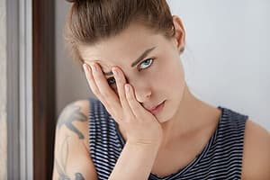 Teenager with her face in hand, embarrassed about the signs of drug use her mom sees.