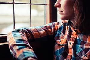 A person in flannel gazes out a window wondering what is meth?