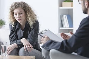 Depressed woman talking to counselor about her methadone abuse.